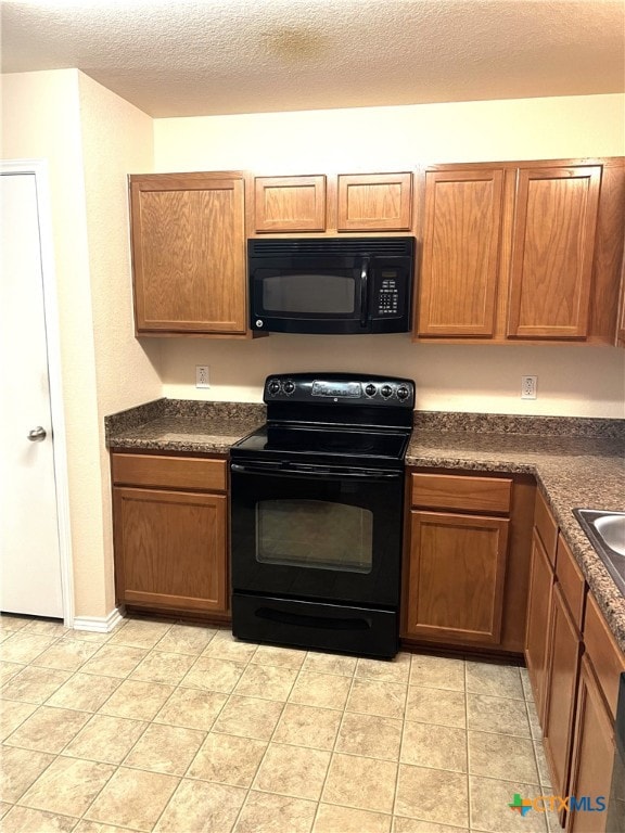 kitchen featuring black appliances, a textured ceiling, and light tile patterned floors