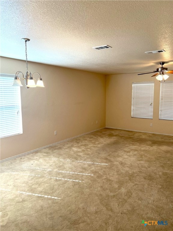 carpeted spare room featuring ceiling fan with notable chandelier and a textured ceiling