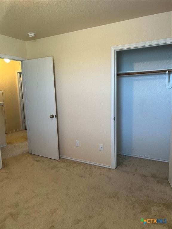 unfurnished bedroom with light carpet and a closet