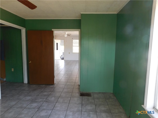 empty room featuring ceiling fan, light tile patterned floors, and ornamental molding