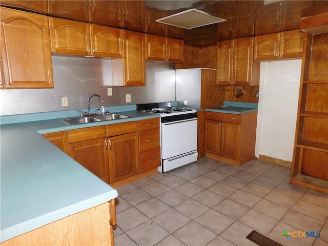 kitchen with light tile patterned floors, sink, and white range oven