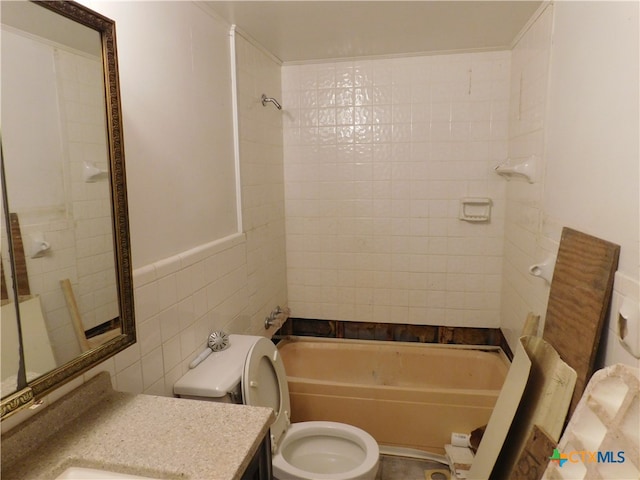 full bathroom with tile walls, tiled shower / bath, toilet, and vanity