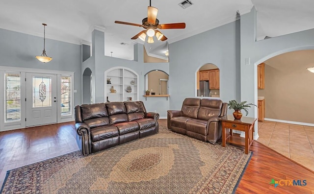 living room featuring wood-type flooring, built in features, and ceiling fan