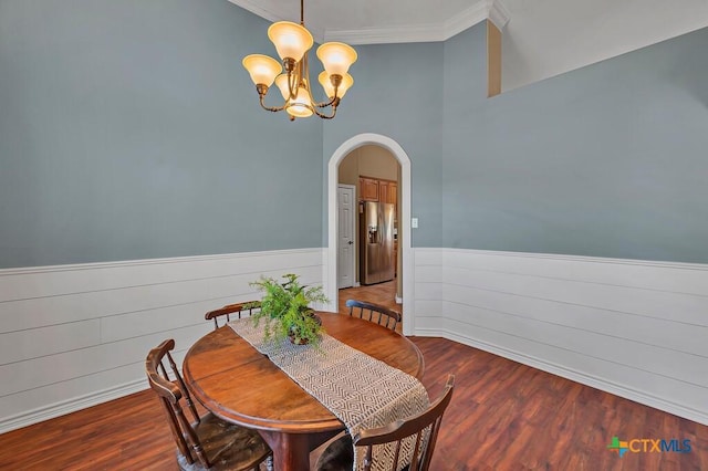 dining space with dark wood-type flooring, ornamental molding, and a chandelier