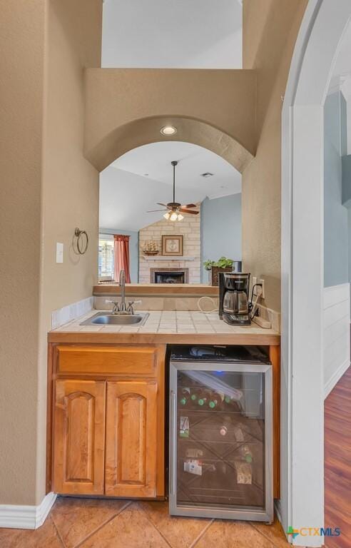 bar with lofted ceiling, sink, ceiling fan, wine cooler, and light tile patterned flooring