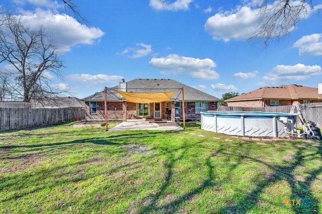 rear view of property featuring a yard, a patio area, and a covered pool