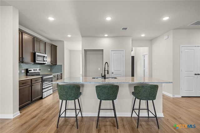 1821 Holleman Dr, Temple, TX 76502 - kitchen featuring appliances with stainless steel finishes, dark brown cabinets, light wood finished floors, and recessed lighting