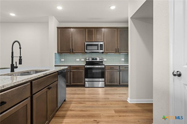 1821 Holleman Dr, Temple, TX 76502 - kitchen featuring stainless steel appliances, light wood-style flooring, backsplash, light stone countertops, and dark brown cabinetry