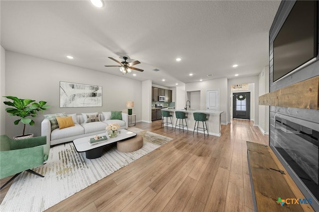 1821 Holleman Dr, Temple, TX 76502 - living room featuring a tile fireplace, light wood finished floors, recessed lighting, and ceiling fan