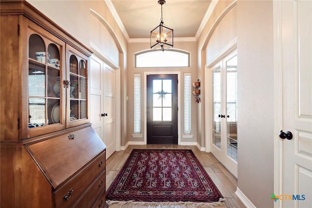 entryway featuring an inviting chandelier, baseboards, and ornamental molding