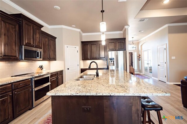 kitchen featuring a sink, tasteful backsplash, light wood-type flooring, and stainless steel appliances