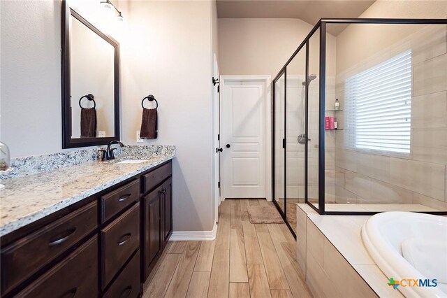 bathroom featuring a bath, a stall shower, vanity, and wood finished floors