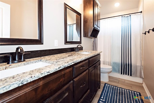 full bathroom featuring a sink, wood finish floors, toilet, and double vanity