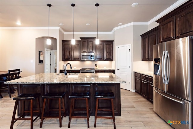 kitchen featuring dark brown cabinets, arched walkways, appliances with stainless steel finishes, and a sink