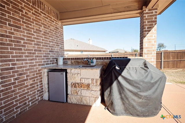 view of patio / terrace featuring a grill, exterior kitchen, a fenced backyard, and a sink