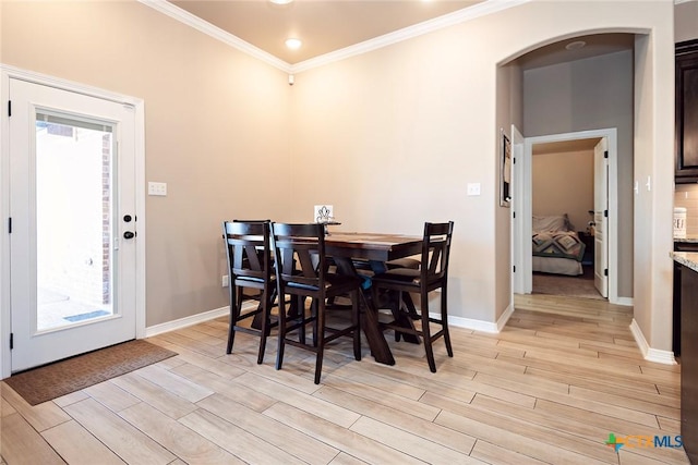 dining space with arched walkways, baseboards, wood finish floors, and ornamental molding