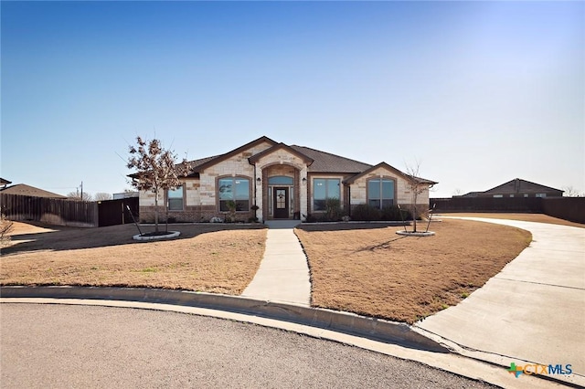 view of front facade with fence and stone siding