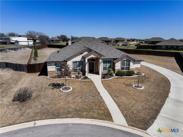 view of front of home with a residential view, stone siding, and fence