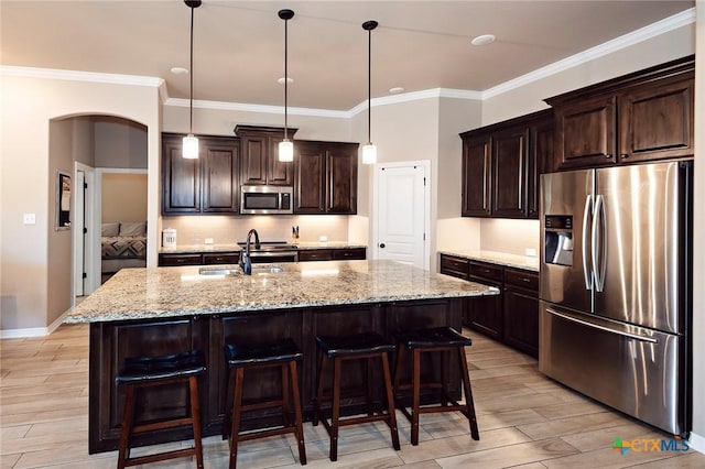 kitchen with arched walkways, stainless steel appliances, wood finish floors, and a sink