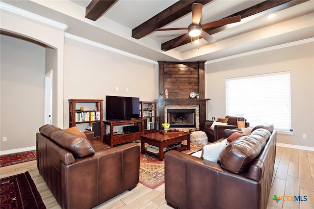 living room with beam ceiling, light wood-style flooring, baseboards, and a large fireplace