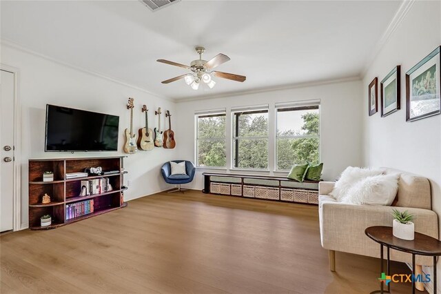 sitting room with wood finished floors, crown molding, and a ceiling fan