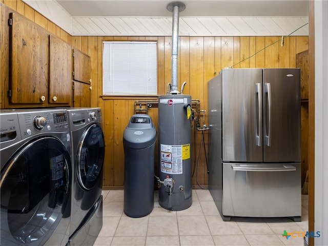 clothes washing area with light tile patterned floors, gas water heater, cabinets, and wooden walls