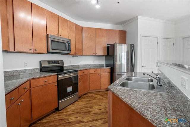 2502 Leon St Unit 201, Austin, TX 78705 - kitchen featuring appliances with stainless steel finishes, a sink, brown cabinetry, dark wood-type flooring, and ornamental molding