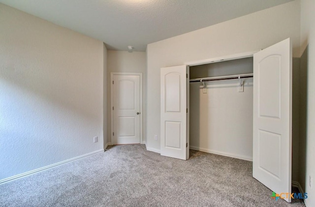 unfurnished bedroom with carpet floors, baseboards, and a closet