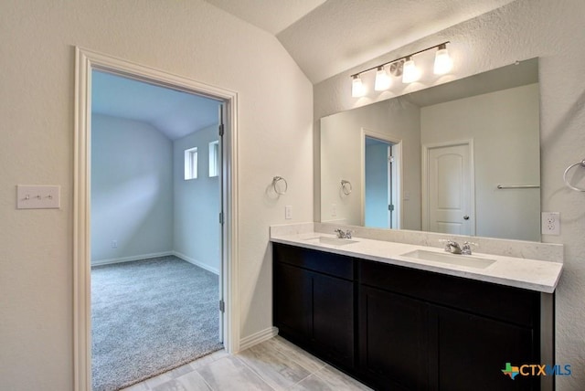full bath with double vanity, lofted ceiling, and a sink
