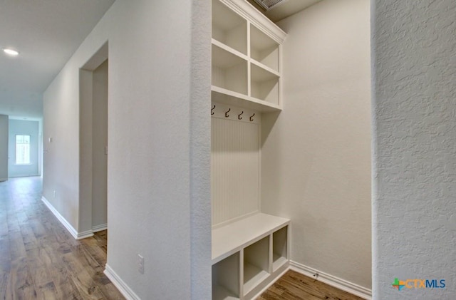 mudroom with a textured wall, baseboards, and wood finished floors