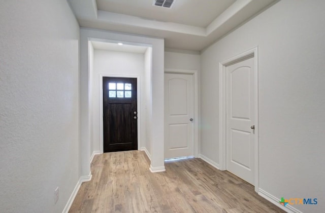 entrance foyer featuring light wood finished floors, baseboards, visible vents, and a raised ceiling