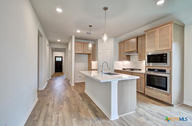 kitchen featuring stainless steel oven, decorative backsplash, a sink, built in microwave, and light wood-style flooring
