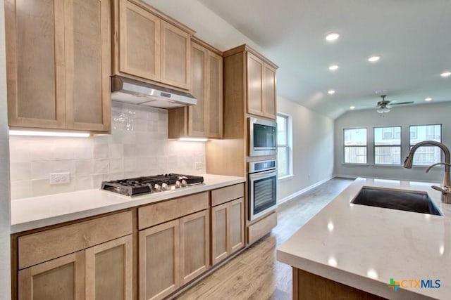 kitchen featuring a sink, a ceiling fan, under cabinet range hood, stainless steel appliances, and decorative backsplash