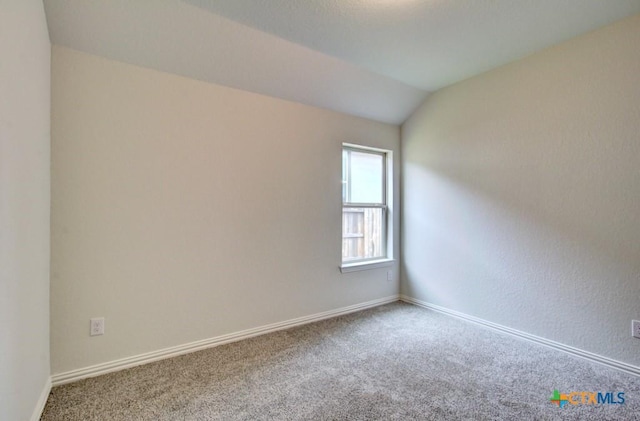 spare room featuring baseboards, vaulted ceiling, and carpet