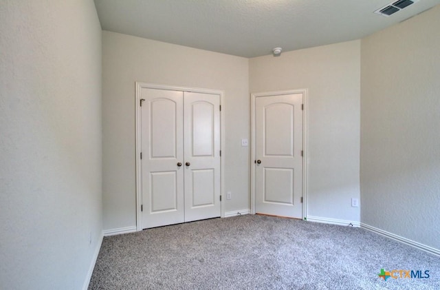 unfurnished bedroom with baseboards, carpet, a closet, and visible vents