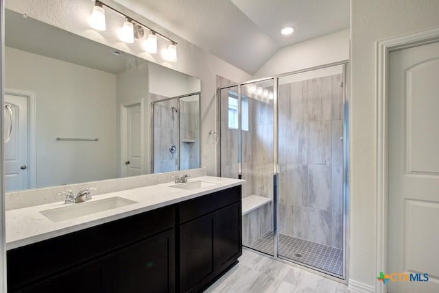 full bathroom with a shower stall, double vanity, lofted ceiling, and a sink