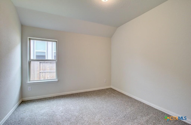 unfurnished room with carpet floors, baseboards, and vaulted ceiling