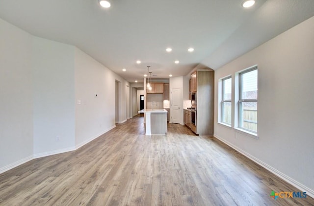 unfurnished living room featuring a sink, baseboards, light wood-style floors, and recessed lighting