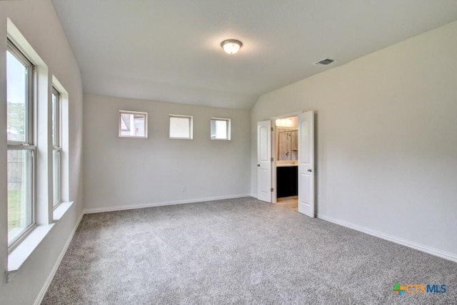 spare room with vaulted ceiling, baseboards, light colored carpet, and visible vents