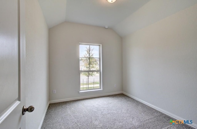 carpeted spare room with baseboards and vaulted ceiling
