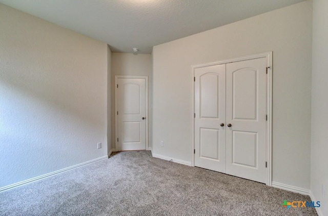 unfurnished bedroom featuring baseboards, a closet, and carpet floors