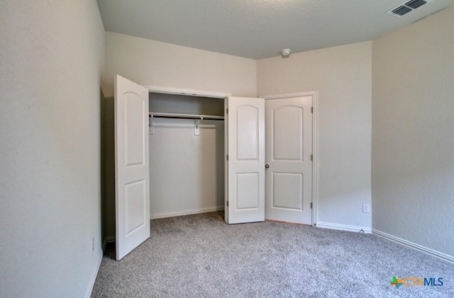 unfurnished bedroom featuring baseboards, visible vents, a closet, and carpet