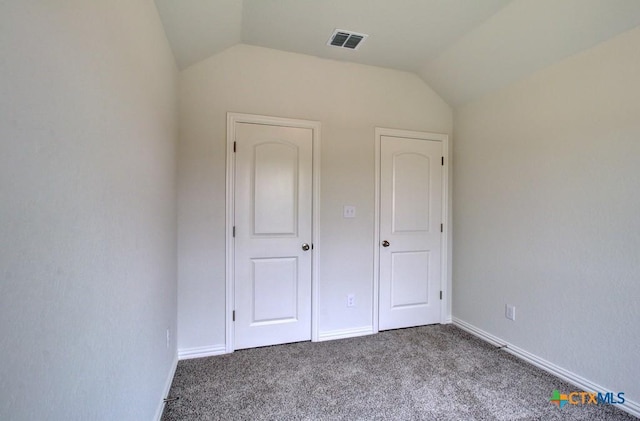 unfurnished bedroom featuring baseboards, visible vents, carpet flooring, and vaulted ceiling