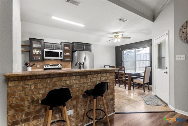 2903 Tucson Dr, Killeen, TX 76543 - kitchen with appliances with stainless steel finishes, ornamental molding, backsplash, glass insert cabinets, and a kitchen breakfast bar