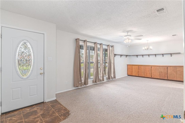 entryway featuring visible vents, ceiling fan with notable chandelier, a textured ceiling, and dark carpet