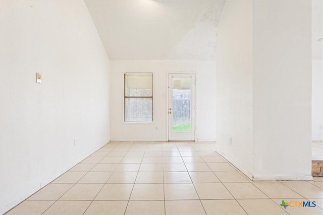 spare room with light tile patterned floors and lofted ceiling