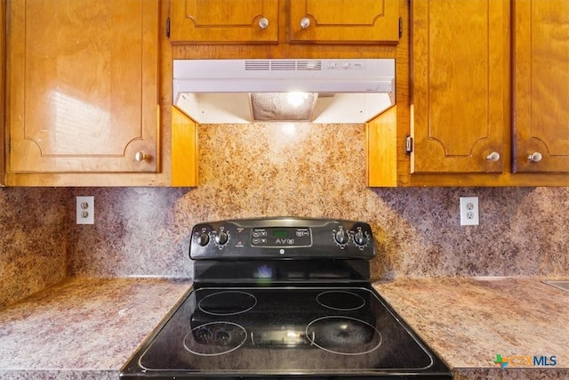 kitchen with backsplash, black range with electric stovetop, and light stone counters