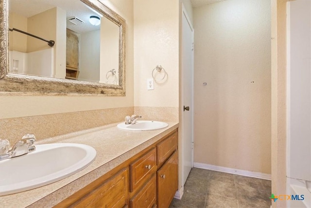 bathroom with a textured ceiling, vanity, and tile patterned floors