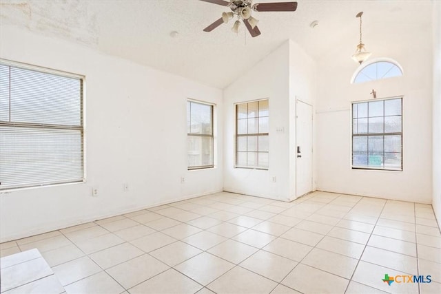 tiled entryway with ceiling fan, high vaulted ceiling, and a textured ceiling