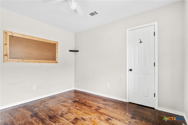 empty room with ceiling fan and dark hardwood / wood-style flooring